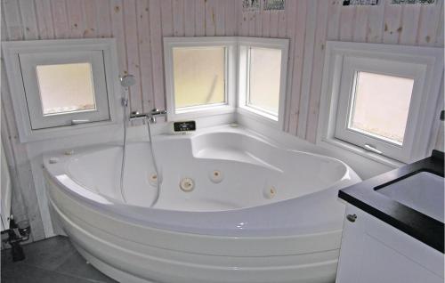 uma banheira branca numa casa de banho com 2 janelas em 3 Bedroom Awesome Home In Tranekr em Skattebølle
