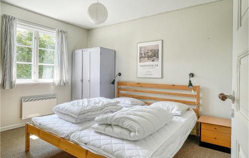 a bedroom with a bed with white sheets and a refrigerator at Gorgeous Home In Gudhjem With Wifi in Gudhjem