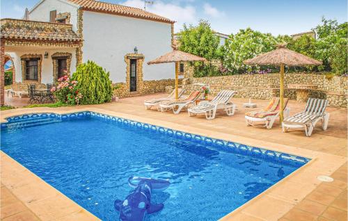 a pool with chairs and umbrellas next to a house at Stunning Home In El Gastor With Wifi in El Gastor