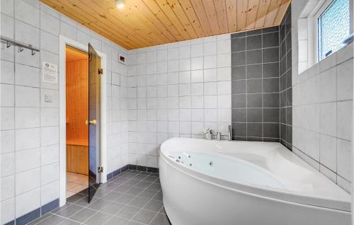 ブラーバンドにあるAmazing Home In Blvand With 4 Bedrooms, Sauna And Wifiの木製の天井のバスルーム(白いバスタブ付)