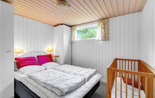 a bedroom with a bed with pink pillows and a crib at Beautiful Home In Blvand With Wifi in Blåvand
