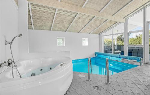 SønderbyにあるStunning Home In Juelsminde With 5 Bedrooms, Sauna And Indoor Swimming Poolのバスルーム(白いバスタブ、青いベンチ付)