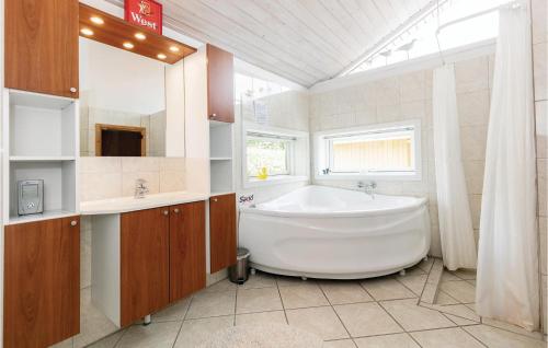 baño con una gran bañera blanca y una ventana en 4 Bedroom Awesome Home In Rnne, en Rønne