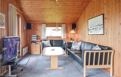 a living room with a couch and a table and a tv at Holiday Home Fyrmarken Hvide Sande Vi in Nørre Lyngvig