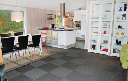 una cucina con mobili bianchi, tavolo e sedie di Holiday Home Romo With A Fireplace 333 a Rømø Kirkeby