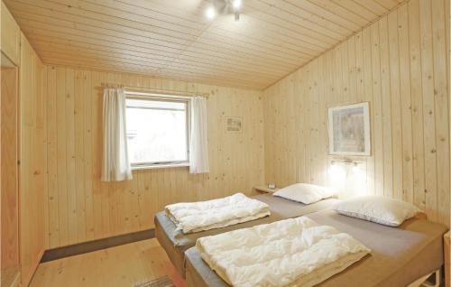BalkeにあるNice Home In Nex With 3 Bedrooms And Wifiのウッドウォールと窓が備わるドミトリールームのベッド2台分です。