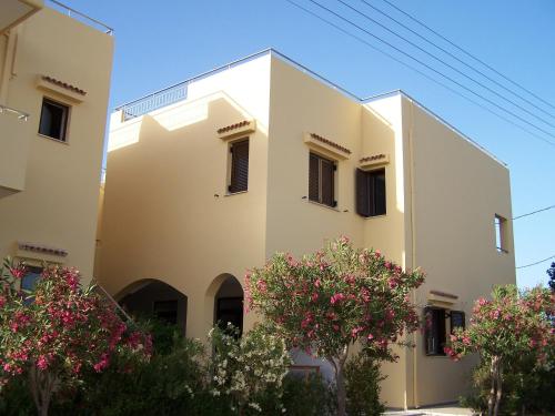 a white building with pink flowers in front of it at Aptera Hotel in Megála Khoráfia