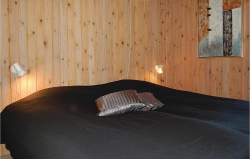 a bedroom with a black bed with a wooden wall at Gorgeous Home In Hvide Sande With Ethernet Internet in Havrvig