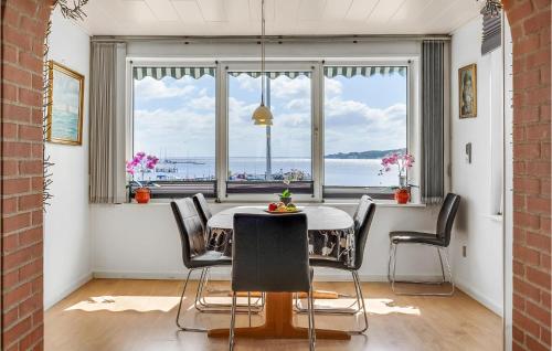 a dining room with a table and chairs and a large window at Holiday Home Sønderballevej Rødekro Ix in Diernæs