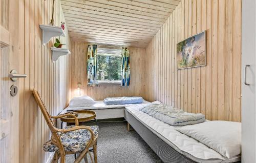 StoenseにあるNice Home In Tranekr With 3 Bedrooms And Saunaのベッド2台と椅子が備わる小さな客室です。