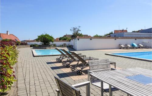 a row of benches next to a swimming pool at Cozy Apartment In Gudhjem in Gudhjem