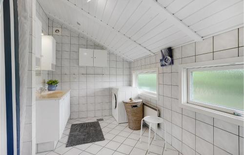 BjerregårdにあるCozy Home In Hvide Sande With Wifiの白いタイル張りのバスルーム(洗面台、トイレ付)