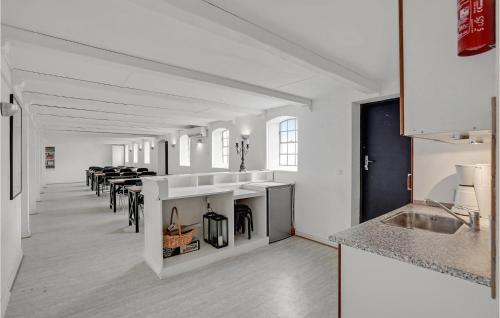 a white kitchen with a bunch of tables and chairs at Amazing Home In Søllested With Wifi in Søllested