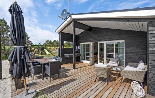 BjerregårdにあるHoliday Home Hvide Sande With A Fireplace 313の木製デッキ(傘、テーブル付)