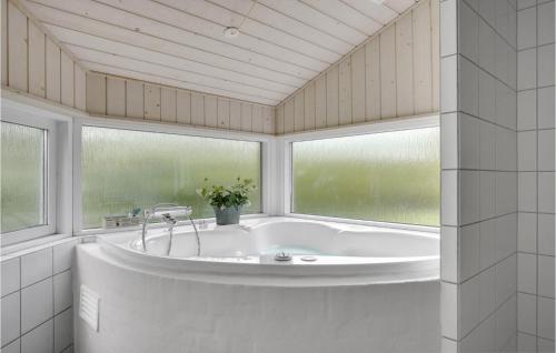 a bath tub in a room with two windows at Cozy Home In Dronningmlle With Sauna in Dronningmølle