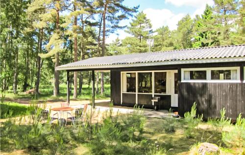 ein kleines schwarzes Haus im Wald mit einer Terrasse in der Unterkunft Beautiful Home In Nexø With Wifi in Vester Sømarken
