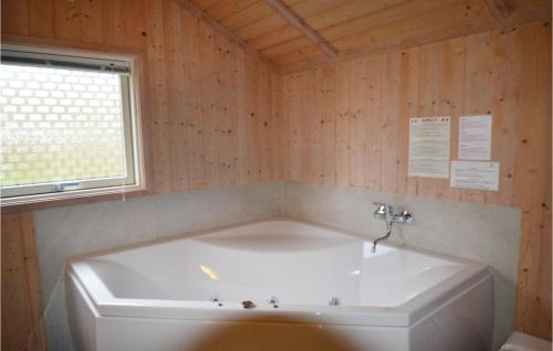La salle de bains est pourvue d'une baignoire blanche et d'une fenêtre. dans l'établissement 4 Bedroom Nice Home In Idestrup, à Bøtø By