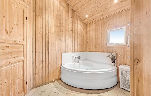 baño con bañera blanca y paredes de madera en Awesome Home In Rudkbing With 5 Bedrooms, Sauna And Wifi, en Spodsbjerg