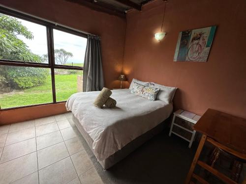 ein Schlafzimmer mit einem Bett mit einem Teddybär drauf in der Unterkunft BlueCottage or Seaview Cottage at Coram Deo Lodge self catering in Coffee Bay