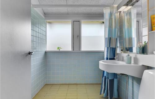 y baño de azulejos azules con lavabo y ducha. en Golfparken, en Løjt