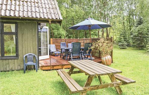 a picnic table with an umbrella in a yard at Two-Bedroom Holiday Home In Frederiksvark in Frederiksværk