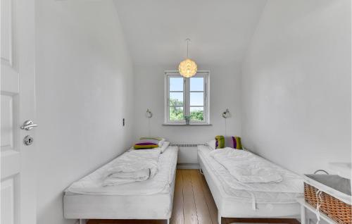 ヒュールスミンネにあるBeautiful Home In Juelsminde With 3 Bedrooms, Wifi And Saunaの白い部屋で、ベッド2台、窓が備わります。