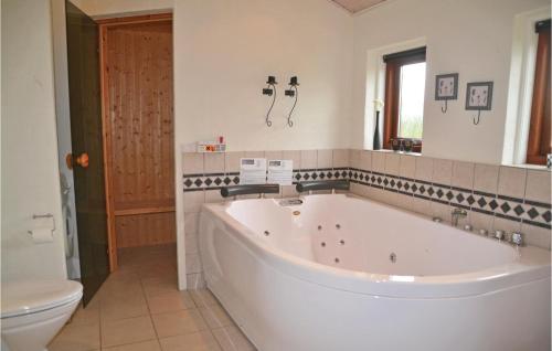 La salle de bains est pourvue d'une grande baignoire blanche et de toilettes. dans l'établissement Cozy Home In Tarm With Sauna, à Tarm