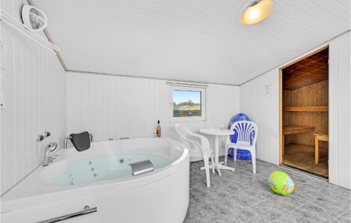 BjerregårdにあるGorgeous Home In Hvide Sande With Wifiのバスルーム(バスタブ、テーブル、椅子付)