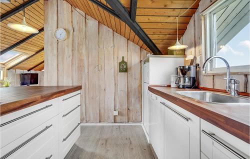 a kitchen with white cabinets and a sink at Holiday Home Romo Lxix in Bolilmark