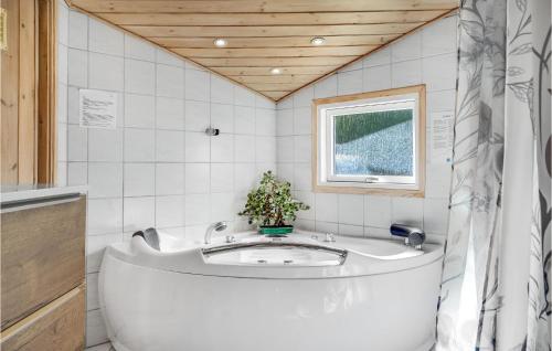 een wit bad in een badkamer met een raam bij Amazing Home In Grenaa With Sauna in Stokkebro