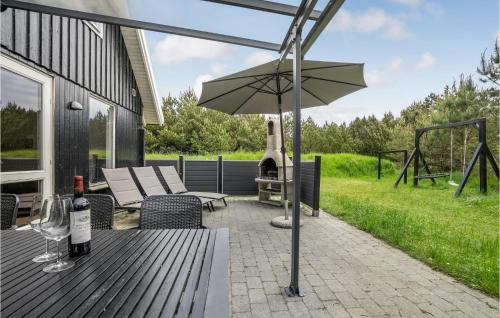 a patio with an umbrella and chairs and a grill at Holiday Home Koubjerg Iii in Toftum