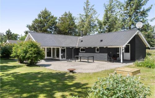 a black house with a picnic table in a yard at Holiday Home Mågelunden Rødby Ii in Kramnitse