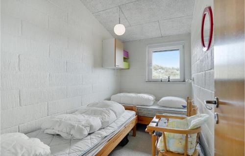 HavrvigにあるNice Home In Hvide Sande With Kitchenのベッド3台と窓が備わる客室です。