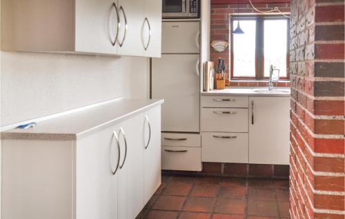 eine Küche mit weißen Schränken und einer Ziegelwand in der Unterkunft Gorgeous Home In Faaborg With Sauna in Fåborg