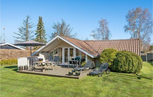 a house with a deck with chairs and an umbrella at Holiday Home Gøgevej Dronningmølle Vi in Dronningmølle