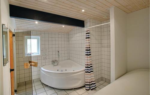a large white tub in a bathroom with a window at Lovely Home In Nex With Sauna in Vester Sømarken
