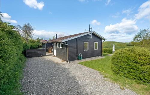 a small black house with a gravel driveway at Holiday Home Træløbervej Tranekær Xi in Lokkeby