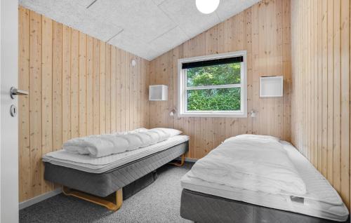 FalenにあるAmazing Home In Hemmet With 3 Bedrooms, Sauna And Wifiのウッドウォールと窓が備わるドミトリールームのベッド2台分です。