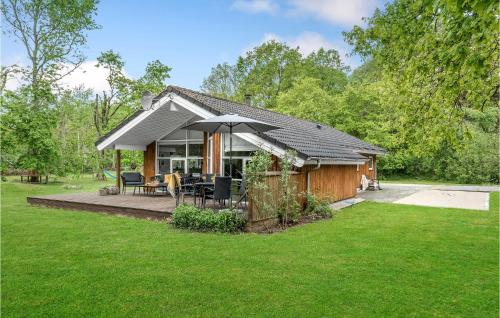 a small house with a deck and an umbrella at 4 Bedroom Cozy Home In Hadsund in Hadsund