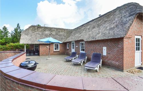 a brick building with a patio with chairs and an umbrella at Holiday Home Rømø 60 in Rømø Kirkeby