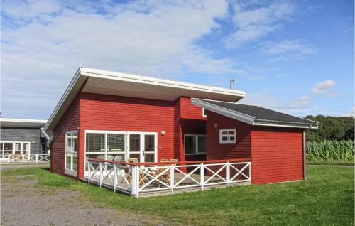 a red house with a large porch in the grass at 2 Bedroom Gorgeous Home In Gudhjem in Gudhjem