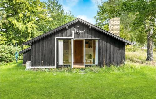a black shed with a door open in a field at 1 Bedroom Awesome Home In Jægerspris in Jægerspris