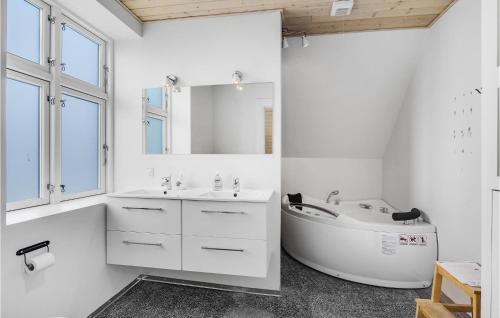 Baño blanco con bañera y lavamanos en Awesome Home In Bagenkop With Kitchen, en Bagenkop