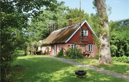a red house with a large tree in front of it at Two-Bedroom Holiday Home In Gilleleje in Gilleleje