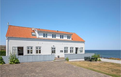 ein weißes Haus mit orangefarbenem Dach und Meer in der Unterkunft Apartment Strandpromenaden Allinge X in Allinge