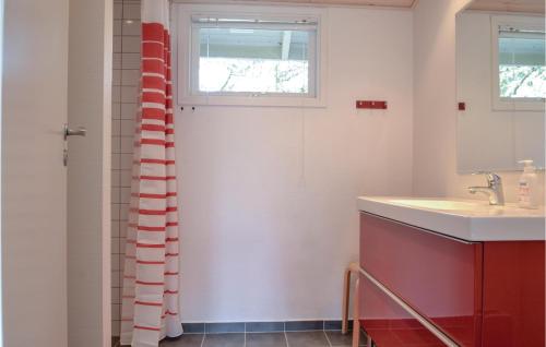 La salle de bains est pourvue d'un lavabo et d'un rideau de douche rouge et blanc. dans l'établissement 3 Bedroom Nice Home In Hvide Sande, à Bjerregård