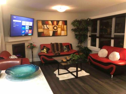 ein Wohnzimmer mit roten Möbeln und einem Flachbild-TV in der Unterkunft Cheerful and beautiful 3 bedroom home close lake in Edmonton