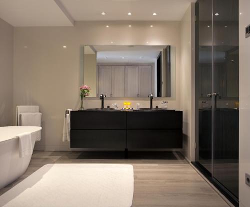 a bathroom with a sink and a tub and a mirror at Hotel AR Golf Almerimar in Almerimar