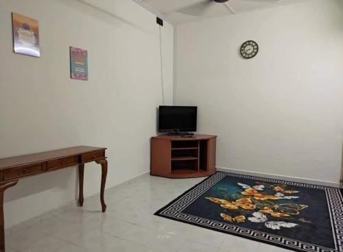 Zimmer mit einem TV, einem Tisch und einem Teppich in der Unterkunft Homestay Kuala Kangsar Private Pool in Kuala Kangsar