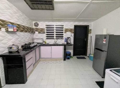 eine Küche mit einem schwarzen Kühlschrank und einem weißen Fliesenboden in der Unterkunft Homestay Kuala Kangsar Private Pool in Kuala Kangsar